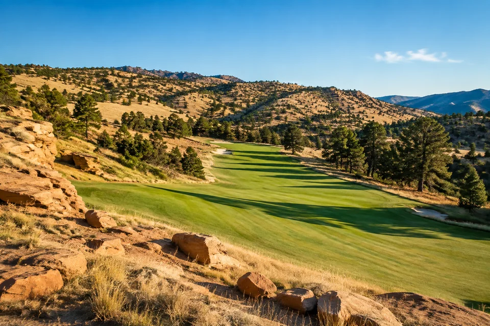 Golf landscape with buff sandstone outcrops beside a winding fairway in dry foothills